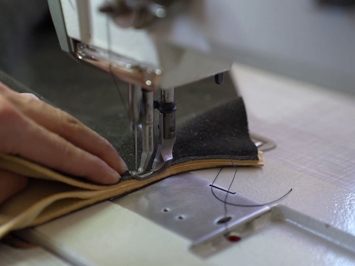 Ein Abend im Zeichen des Handwerks Hand führt Leder durch eine Nähmaschine beim Nähen