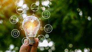 News Hand hält Glühbirne mit Symbolen für erneuerbare Energiequellen und Nachhaltigkeit