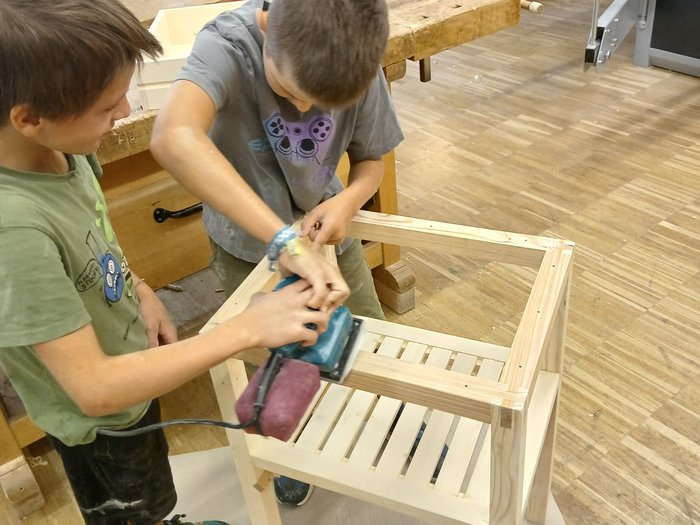 Mit Holz, Wasser & Handwerksfreude: Die KidsAcademy ist in Bruneck angekommen Zwei Jungen schleifen gemeinsam ein Holzstuhlgestell in einer Werkstatt