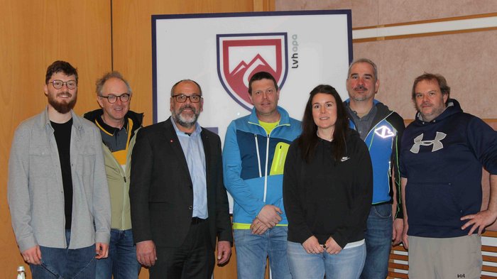 20 Jahre in der richtigen Spur Gruppenfoto von sieben Personen vor einem Schild mit Bergen und Schriftzug LVH apo