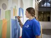 Home Junge Frau malt bunte geometrische Formen an eine Wand