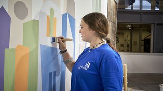 News Ragazza dipinge forme geometriche colorate su una parete