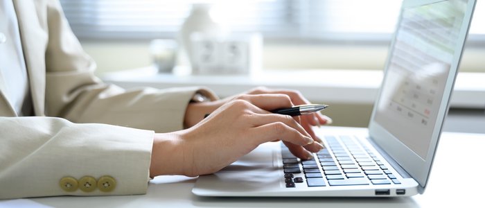 Steuerberatung, Buchhaltung und Lohnabrechnung Person tippt mit einem Stift in der Hand auf einem Laptop am Schreibtisch