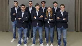 News Gruppe junger Erwachsener in Jeans und Blazern vor grauer Wand