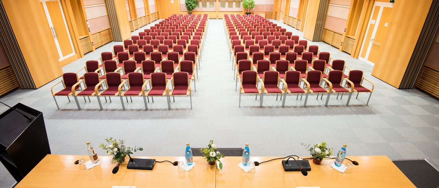 Affitto aule seminari Sala conferenze vuota con sedie rosse e tavolo con microfoni