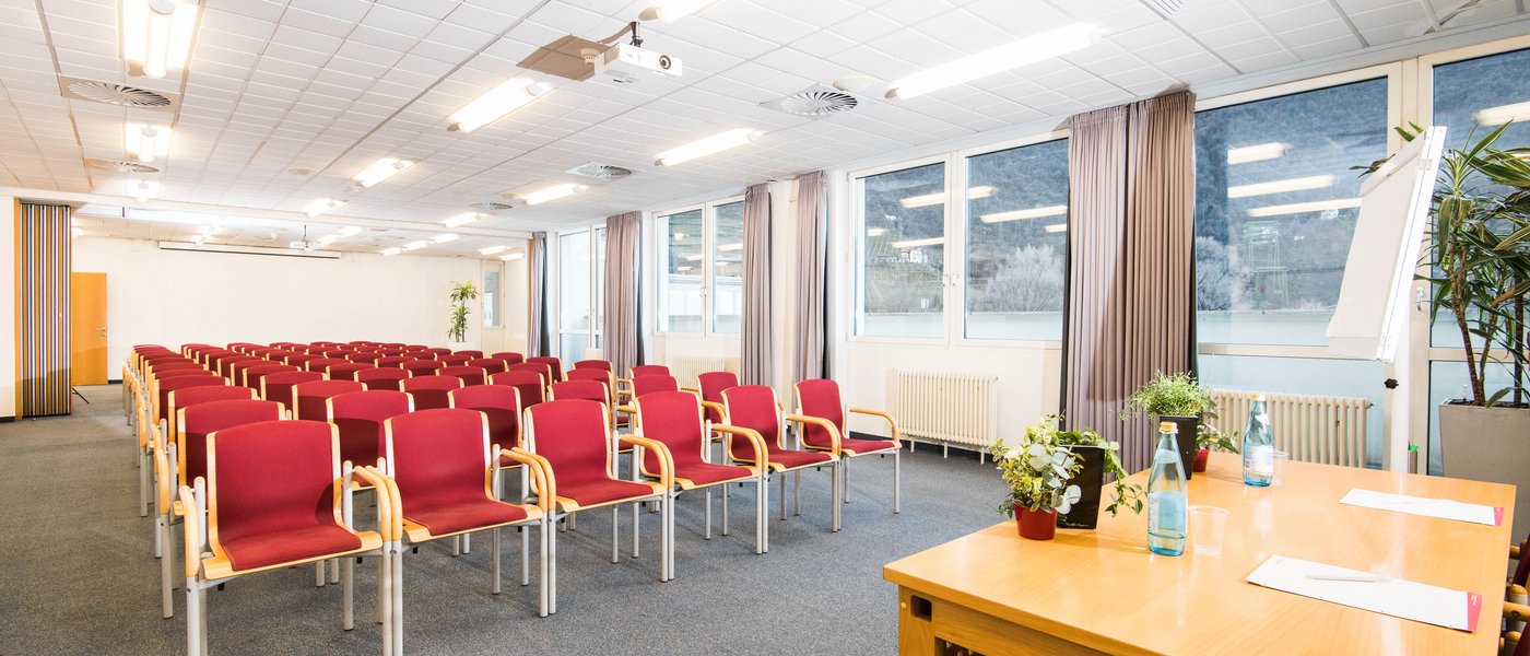 Vermietung Seminarräume Konferenzraum mit roten Stühlen und Tischen im Vordergrund