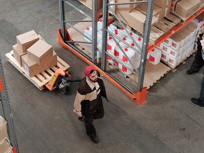 Knappe Rohstoffe, Aufruf der Unternehmen: strategische Produktion zurück nach Europa holen Lagerarbeiter transportiert Kartons, zwei Kollegen prüfen Liste in Lagerhalle