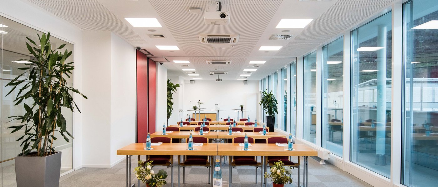 Affitto aule seminari Sala conferenze moderna con file di tavoli, sedie e bottiglie d'acqua