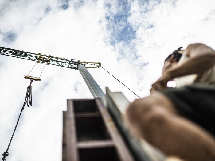 © Hannes Niederkofler Blick nach oben auf einen Baukran und eine Person im Vordergrund