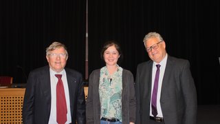 News Drei Personen in formeller Kleidung vor einem schwarzen Hintergrund