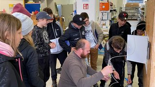 News Mann zeigt Jugendlichen in Werkstatt elektrische Verkabelung