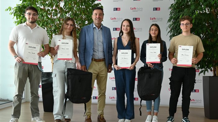 Nachwuchsförderung in der Praxis Gruppe junger Menschen mit Diplomen und Rucksäcken vor LVH-Hintergrund