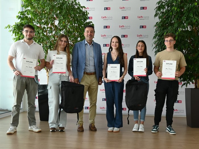 Nachwuchsförderung in der Praxis Gruppe junger Menschen mit Diplomen und Rucksäcken vor LVH-Hintergrund