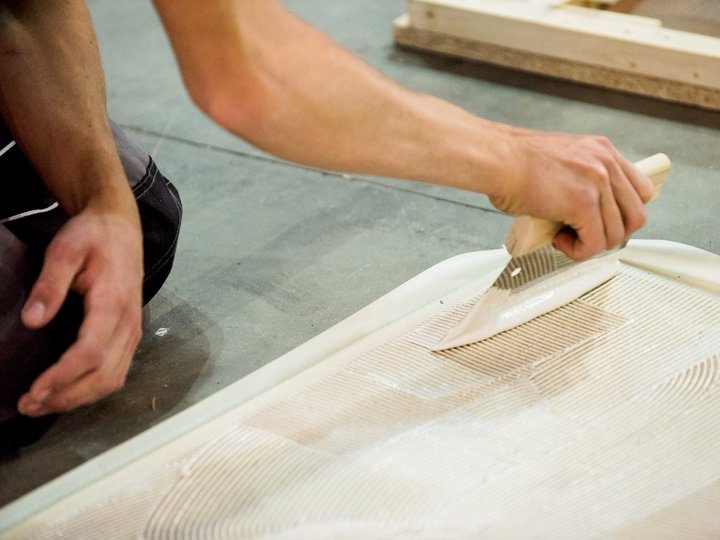 Percorso formativo Persona stende colla per piastrelle con spatola dentata sul pavimento
