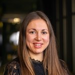 Bozen Land Porträt einer lächelnden Frau mit langen braunen Haaren vor dunklem Hintergrund