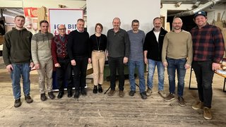 News Gruppe von elf Menschen steht vor Leinwand in Innenraum