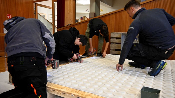 Tag des Handwerks in Jenesien Vier Männer arbeiten zusammen an einer großen weißen Platte mit Elektrowerkzeugen