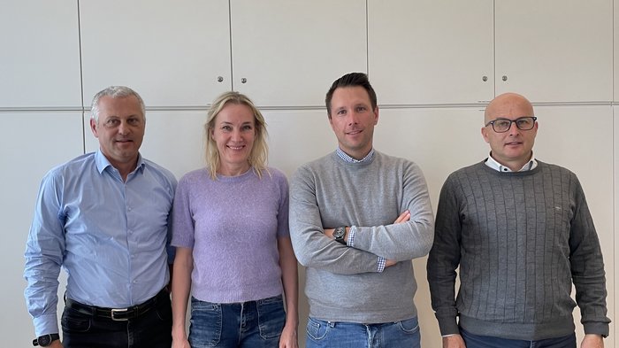 Konstruktiver Dialog: Baugruppe, Architektenkammer Bozen und archacademy erörtern Schlüsselthemen der Branche Vier Personen stehen nebeneinander vor einem weißen Schrank