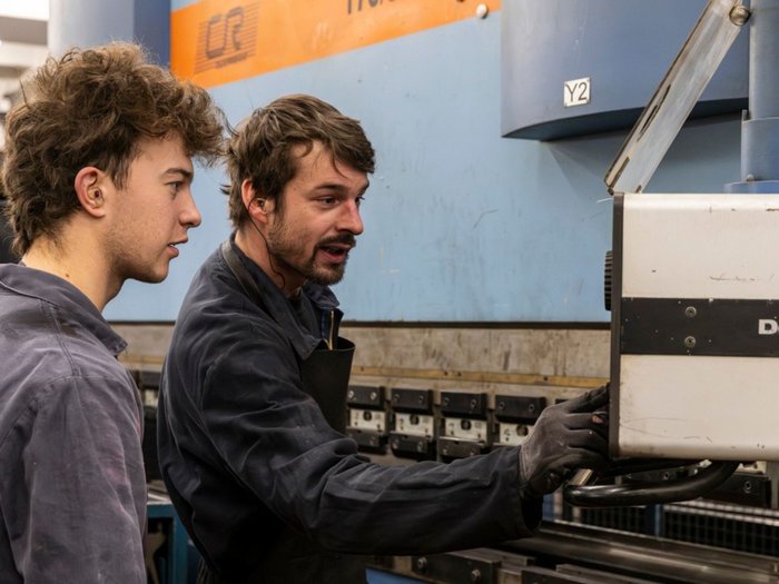 Premio per la formazione degli apprendisti: l’aumento rafforza il valore della formazione professionale Due uomini azionano insieme un macchinario industriale in un'officina