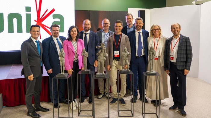 La 31^ Fiera d’Arte UNIKA apre le porte a Ortisei Foto di gruppo con dieci persone e cinque statue su piedistalli durante un evento
