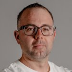 Obervinschgau Porträt eines Mannes mit Brille und weißem T-Shirt vor grauem Hintergrund