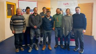 News Gruppenfoto von acht Personen vor zwei Werbebannern in einem Raum