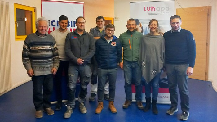 Martin Weiss als Ortsobmann bestätigt Gruppenfoto von acht Personen vor zwei Werbebannern in einem Raum