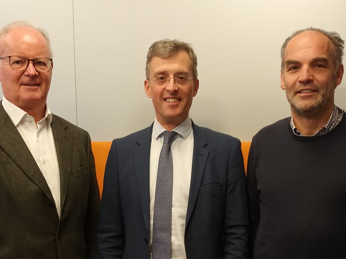 Le imprese della logistica e del trasporto unite per una mobilità efficiente lungo l'asse del Brennero Tre uomini in piedi davanti a una parete bianca con sfondo arancione