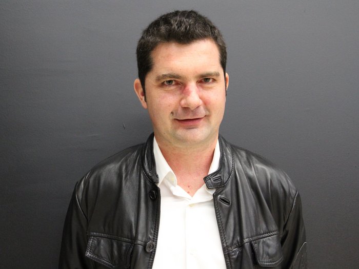 Lohnausgleich sorgt für Unmut in Baubranche Porträt eines Mannes mit schwarzer Lederjacke vor grauer Wand