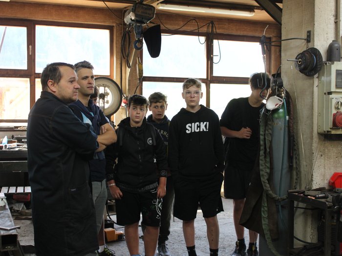 Esplorare nuovi saperi: il mondo delle professioni pratiche Gruppo di giovani e un uomo in un'officina con attrezzature meccaniche