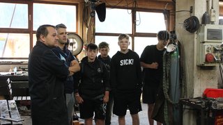 News Gruppe von Jugendlichen und einem Mann in Werkstatt mit Maschinenausrüstung