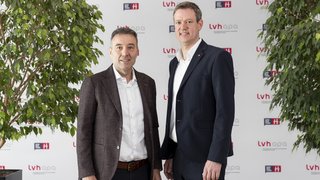 News Zwei Männer im Anzug stehen vor einer lvhapa gesponserten Wand zwischen zwei Pflanzen