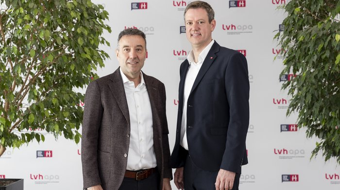 lvh unterzeichnet „Think Small First“-Charta: Starkes Signal für kleine und mittlere Betriebe Zwei Männer im Anzug stehen vor einer lvhapa gesponserten Wand zwischen zwei Pflanzen