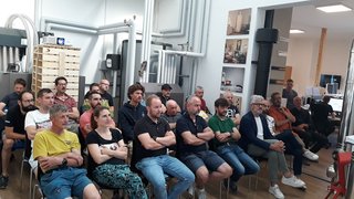 Jahresversammlung der Hafner im lvh – Foto: © lvh.apa Gruppe von Menschen sitzt aufmerksam in einem Raum mit vielen Rohren und Geräte