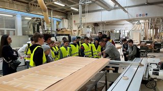 News Gruppe von Kindern in Sicherheitswesten in einer Holzwerkstatt bei einer Führung