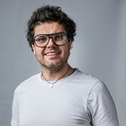 Fotografi e videomaker Uomo sorridente con occhiali e maglietta bianca su sfondo grigio