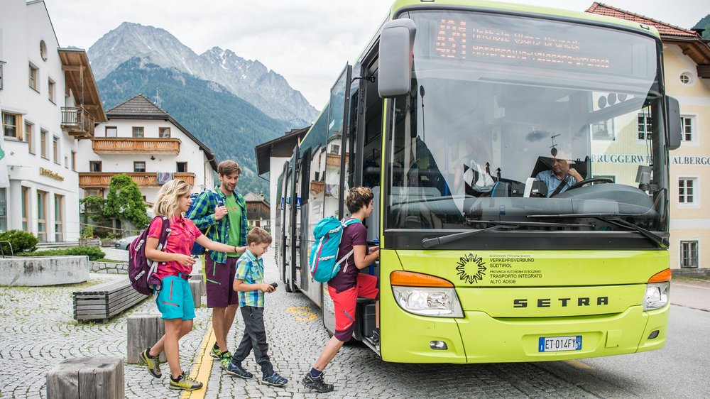 Home Famiglia sale su autobus verde in città di montagna con case tradizionali