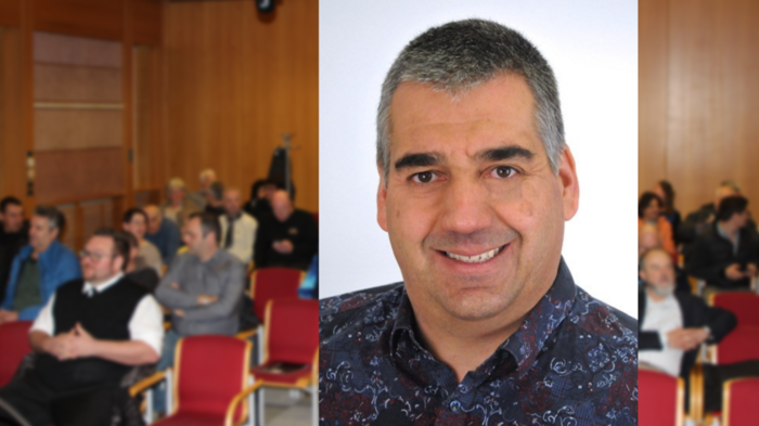 Mietwagenunternehmer: Jahresrückblick und Ehrung des Obmanns Porträt eines lächelnden Mannes vor Publikum in einem Konferenzraum