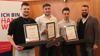 News Drei Männer mit Zertifikaten und eine vierte Person in formeller Kleidung