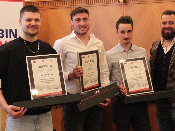 Fieri dell'artigianato e del futuro: i macellai altoatesini celebrano la loro professione, i giovani talenti e la qualità Tre uomini con certificati e una quarta persona in abbigliamento formale