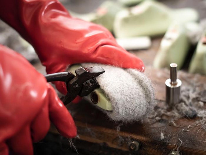 Junghandwerker/innen im lvh und Hoteliers- und Gastwirtejugend (HGJ) zu Gast in der Mittelschule der Ursulinen in Bruneck Person entfernt Filzwolle mit Zange von Schuhsohle