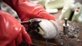 News Person entfernt Filzwolle mit Zange von Schuhsohle