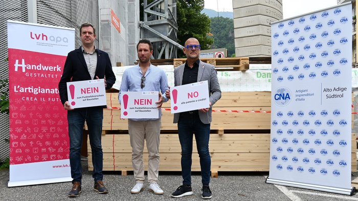 NEIN zum Punkteführerschein, JA zu klaren Zugangsvoraussetzungen für Berufe Tre uomini tengono cartelli con no al patentino a punti sui cantieri