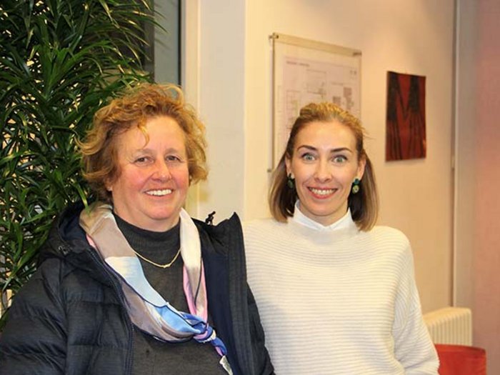 Körperpflege: „Bitte keine Hausbesuche zurzeit!“ Zwei lächelnde Frauen stehen zusammen vor einer Pflanze in Innenraum