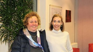 News Zwei lächelnde Frauen stehen zusammen vor einer Pflanze in Innenraum