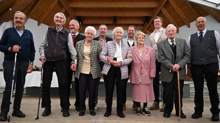 61° incontro degli artigiani anziani a Lutago: un'esperienza indimenticabile Gruppo di anziani e alcuni uomini più giovani su un palco con soffitto in legno