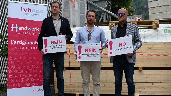 Patente a crediti nei cantieri, tante criticità e incertezze Tre uomini tengono cartelli con no alla patente a crediti sui cantieri