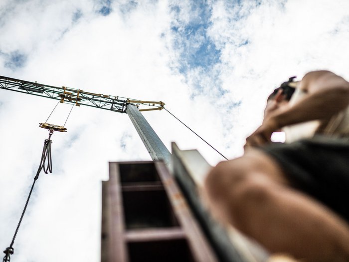 Webinar zum neuen Vergabegesetz - wesentliche Erleichterungen für kleine- und mittelständische Unternehmen Blick nach oben auf einen Kran und eine Person vor bewölktem Himmel