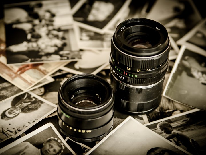 Fotografi e videomaker Due obiettivi fotografici su una pila di vecchie foto in bianco e nero