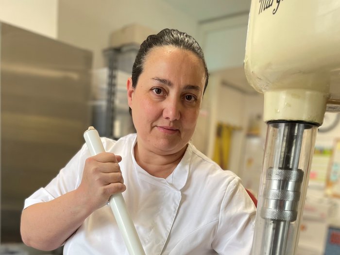 Gelato artigianale: una specialità da gustare consapevolmente Donna con giacca da cucina bianca al lavoro in cucina industriale